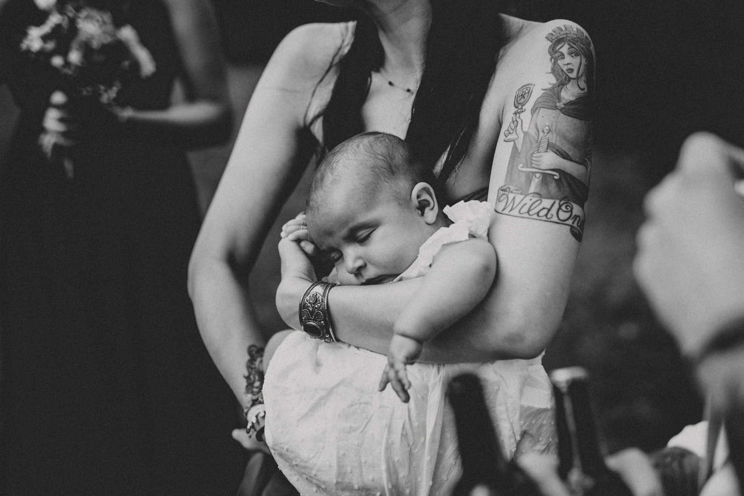 baby in the arms of tattooed bridesmaid on a boho wedding in portugal